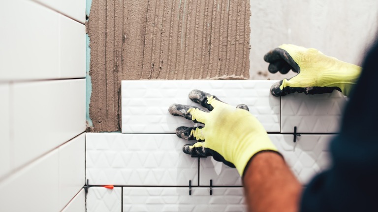 Construction worker installing small ceramic tiles on bathroom walls picture id679511934